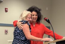 two women hugging each other in front of a podium