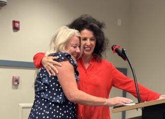 two women hugging each other in front of a podium