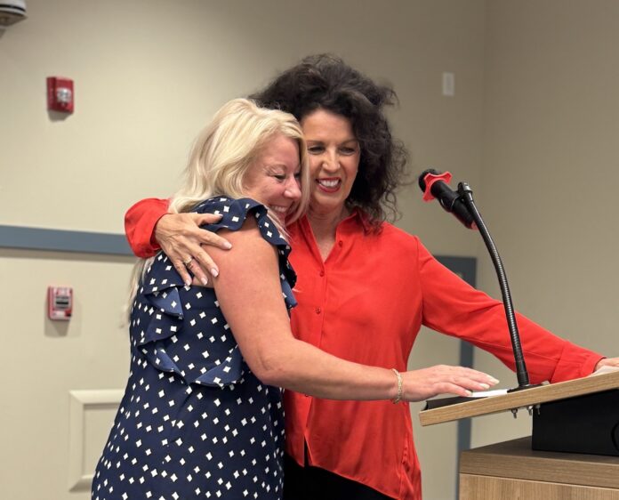 two women hugging each other in front of a podium