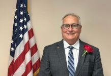 a man in a suit and tie standing next to an american flag