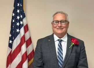 a man in a suit and tie standing next to an american flag