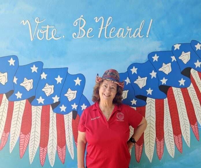 a woman standing in front of a painting of an eagle