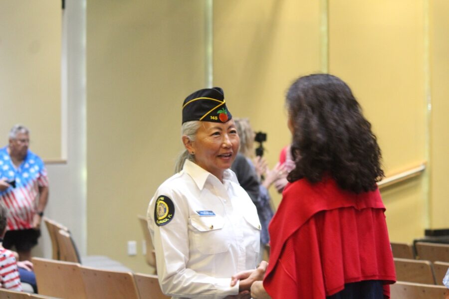 a woman in a uniform shaking hands with a woman in a red dress