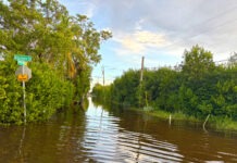 a flooded street with a street sign in the middle of it