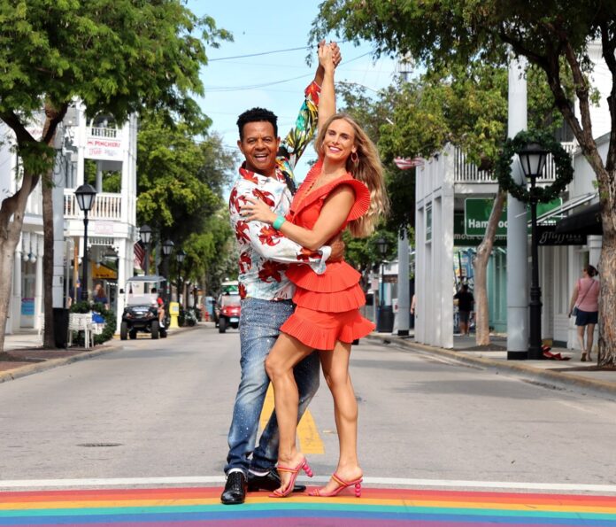 a man and a woman dancing on a rainbow painted street