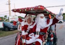 a man and woman dressed as santa clause riding in a golf cart