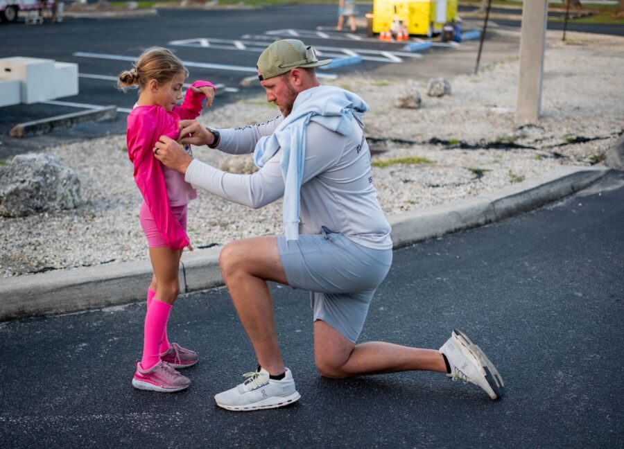 a man kneeling down next to a little girl