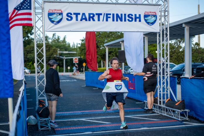 a man running in a marathon under a start finish sign