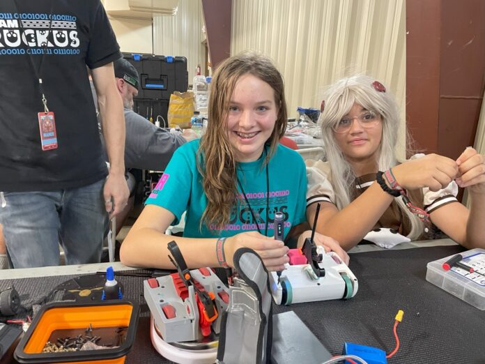 a group of people sitting at a table with electronics