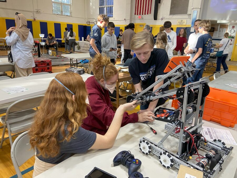 a group of people standing around a table with a robot on it