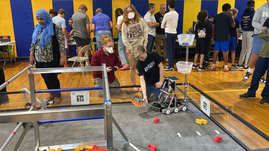 a group of people standing around a table with a robot on it