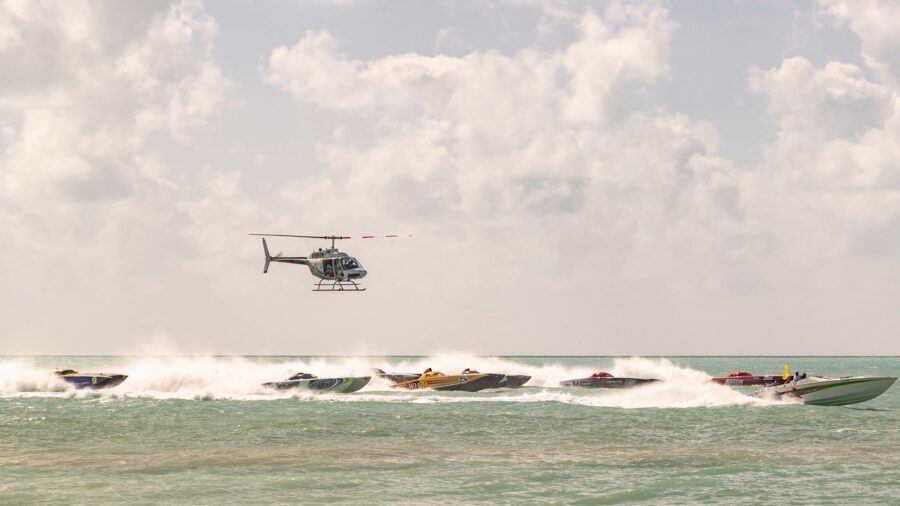 a helicopter flying over a group of boats in the ocean