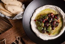 a plate of hummus with olives and bread