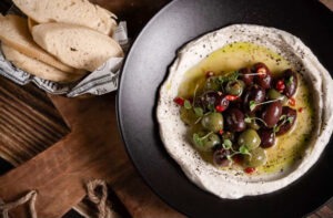 a plate of hummus with olives and bread