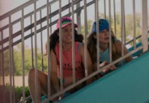 two girls are sitting on the stairs of a roller coaster