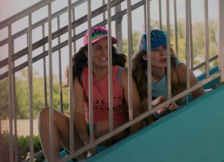 two girls are sitting on the stairs of a roller coaster