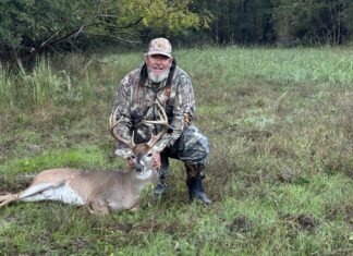 a man kneeling down next to a deer