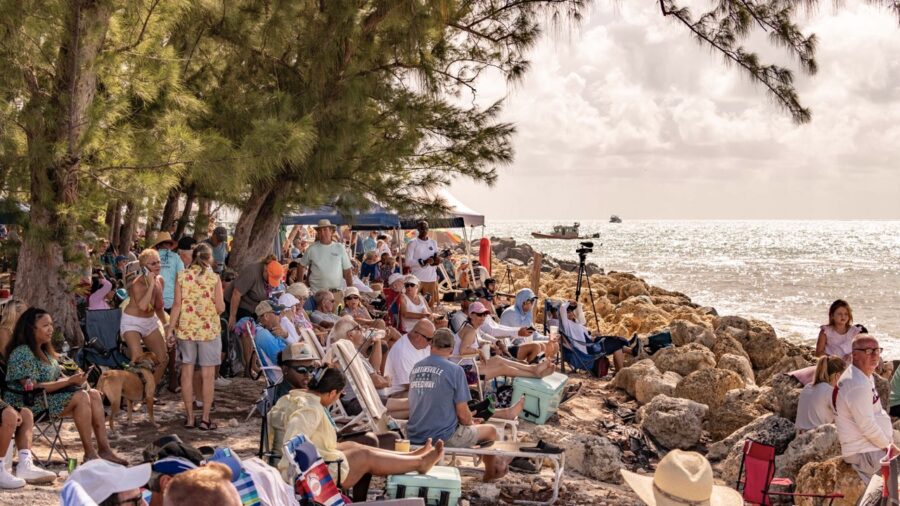 a crowd of people sitting on top of a beach next to the ocean