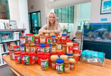 a woman standing behind a table full of jars of food