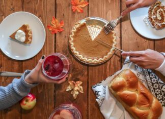 person slicing pie beside bread