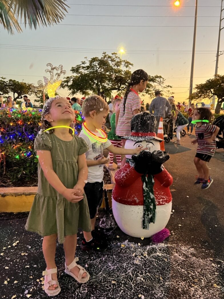 a group of children standing around a snowman