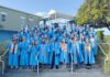 a group of people in blue graduation gowns posing for a picture