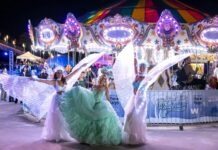 a group of women in dresses dancing in front of a carousel