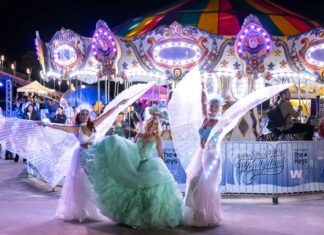 a group of women in dresses dancing in front of a carousel