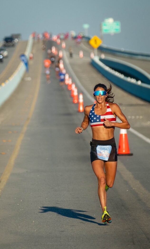 a woman running down a road with an american flag on her shirt