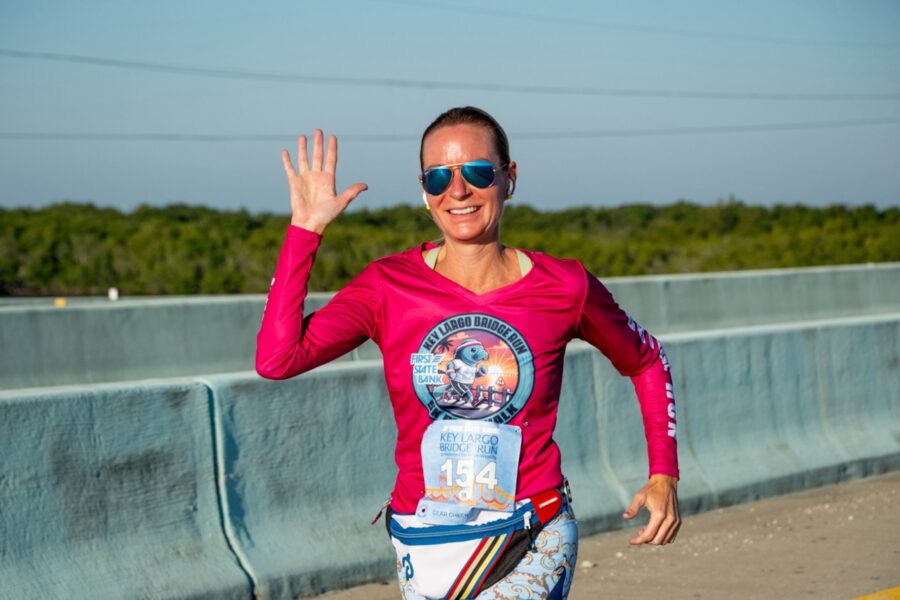 a woman in a pink shirt running across a bridge