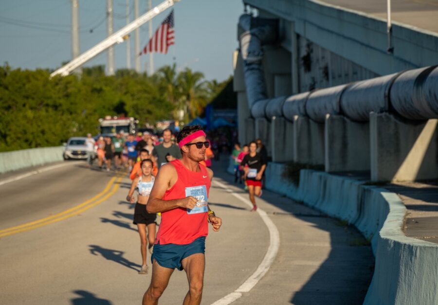 a man in a red shirt running on a bridge