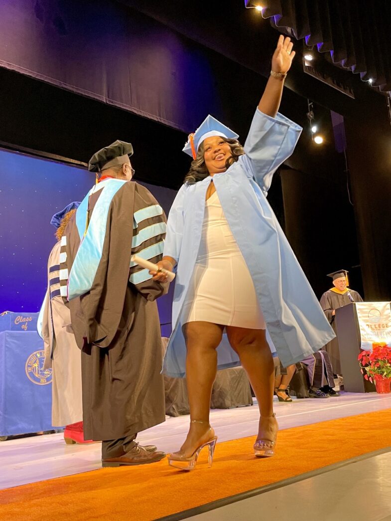 a woman in a graduation gown is walking on a stage