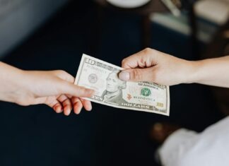 Two people exchanging a ten dollar bill in a close-up hand-to-hand transaction.