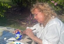 a woman painting a picture on a table outside