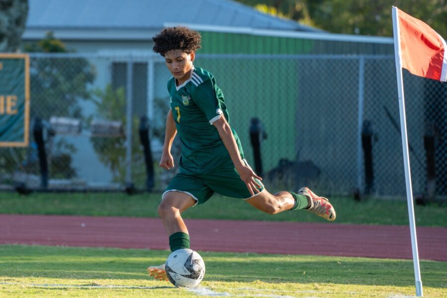 a young man kicking a soccer ball on a field