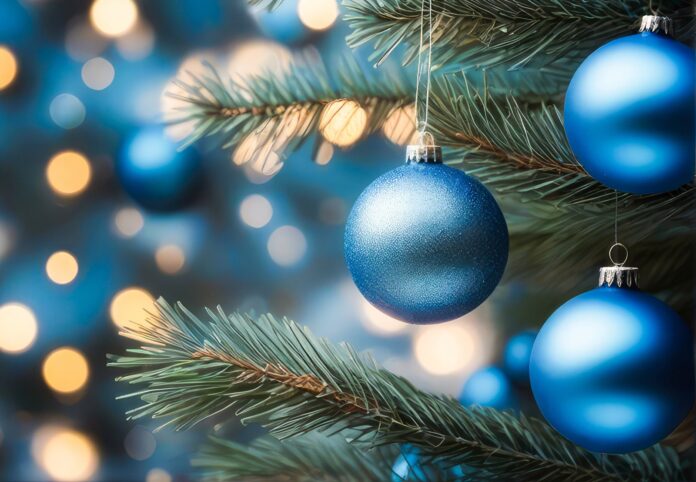 Blue Christmas ornaments in vibrant blue and silver, hanging tree branch with warm bokeh lights , glowing softly in the evening light. a christmas tree with blue ornaments hanging from it
