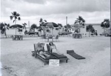 a man laying on top of a chaise lounge on a beach