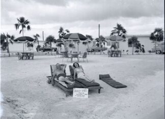 a man laying on top of a chaise lounge on a beach