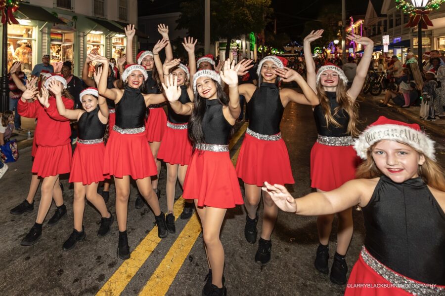 a group of women dressed in red and black dancing in the street