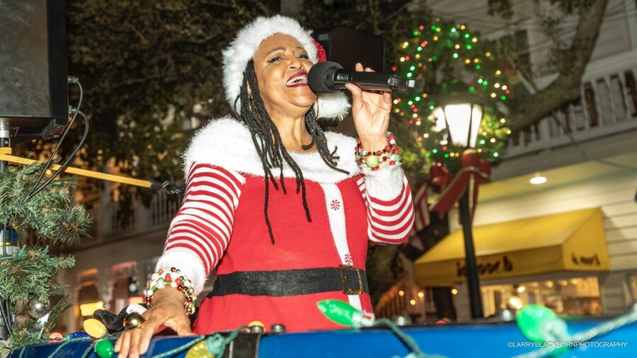 a woman in a santa suit singing into a microphone