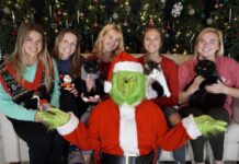 a group of women sitting next to each other in front of a christmas tree