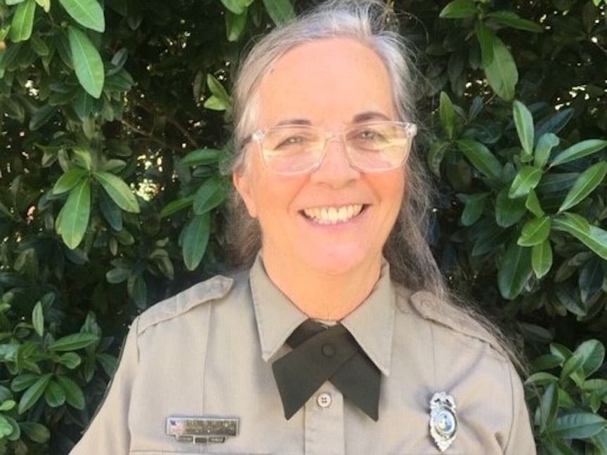 a woman in a uniform standing in front of a bush