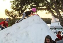 a group of people standing around a pile of snow