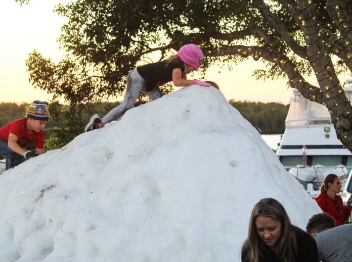 a group of people standing around a pile of snow