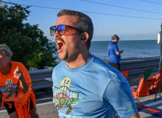 a man in a blue shirt is running by the water