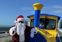 a man dressed as santa clause standing next to a train