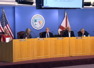 a group of people sitting at a table in front of a screen