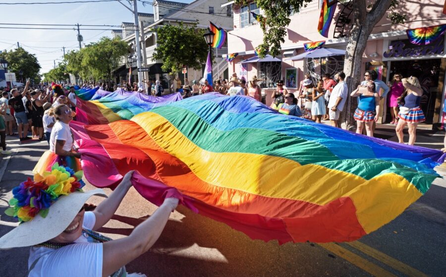 a group of people walking down a street holding a rainbow flag