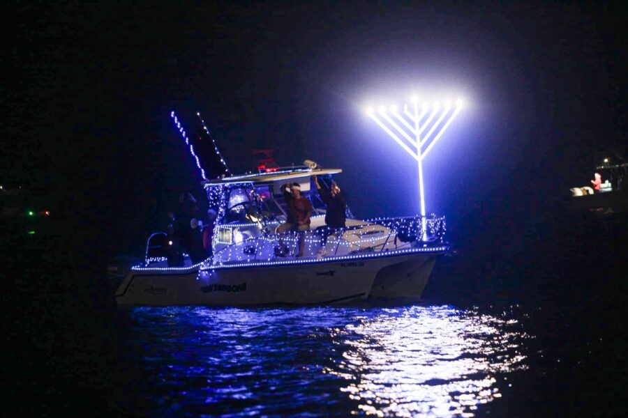 a boat with a lit up menorah on it in the water