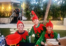 three people dressed in elf costumes sitting at a table